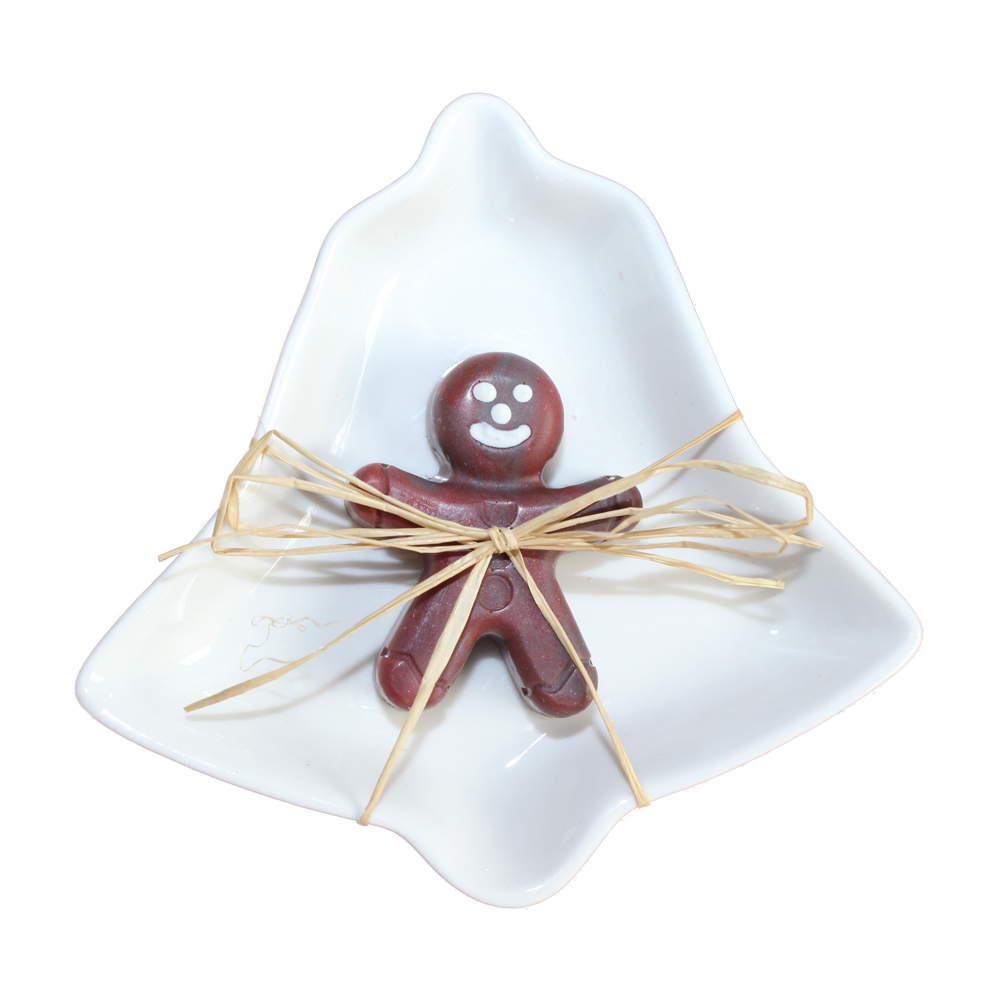 Hier liegt eine kleines Lebkuchenmännchen Seife in rotbraun mit weißem lachenden Gesicht auf einer weißen Keramikseifenschale