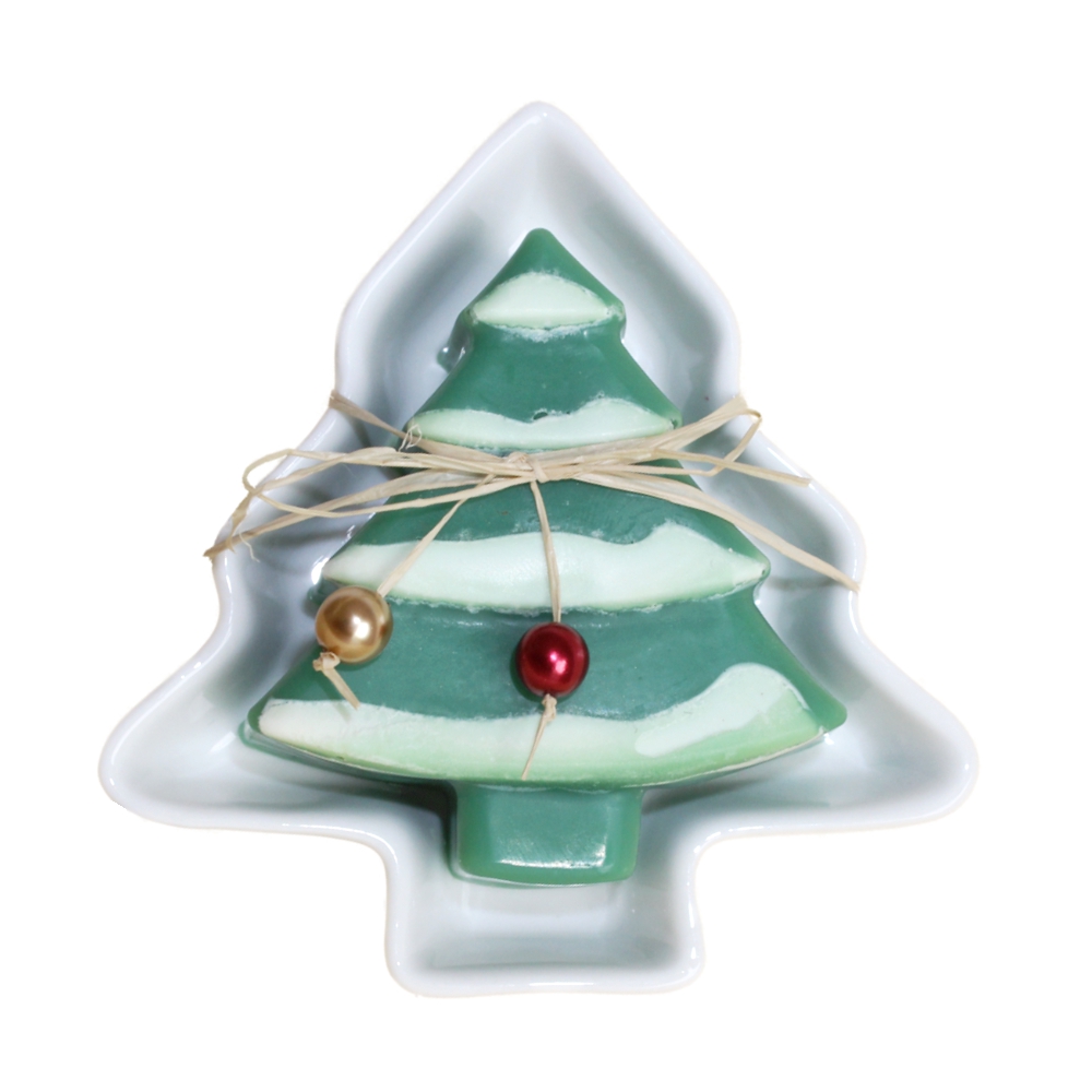 Grünes Seifenstück in Form eines Weihnachtsbaums mit Schneekante. Diese liegt auf einer weißen baumförmigen Keramikseifenschale. Verziert mit bunten Perlen und Bastband.