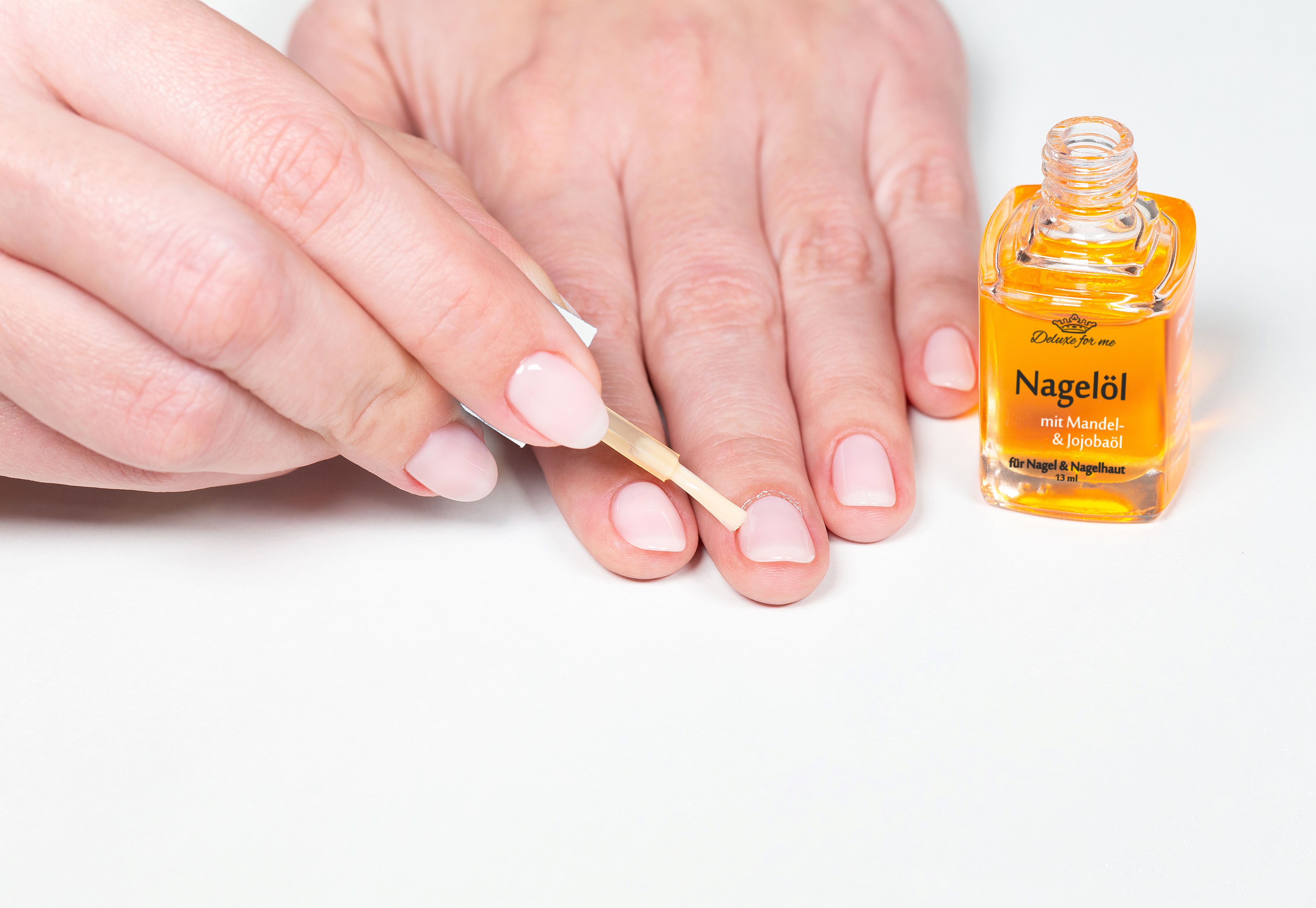 Nagelöl Nahaufnahme von Frauenhänden die gerade ein Nagelöl aufträgt.