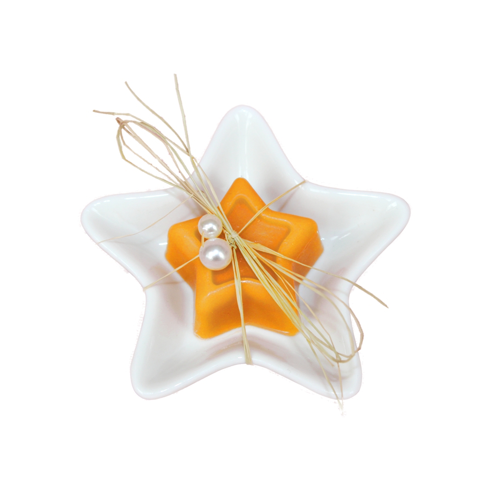 Orange kleine Sternseife auf einer weißen Keramikseifenschale in Sternform gebunden mit einem beigen Bastband und weißen Perlen als Deko.