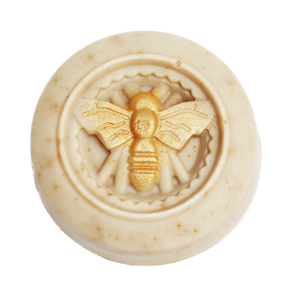 Eine rund Seife mit einem goldenen Bienenmotiv in der Mitte.