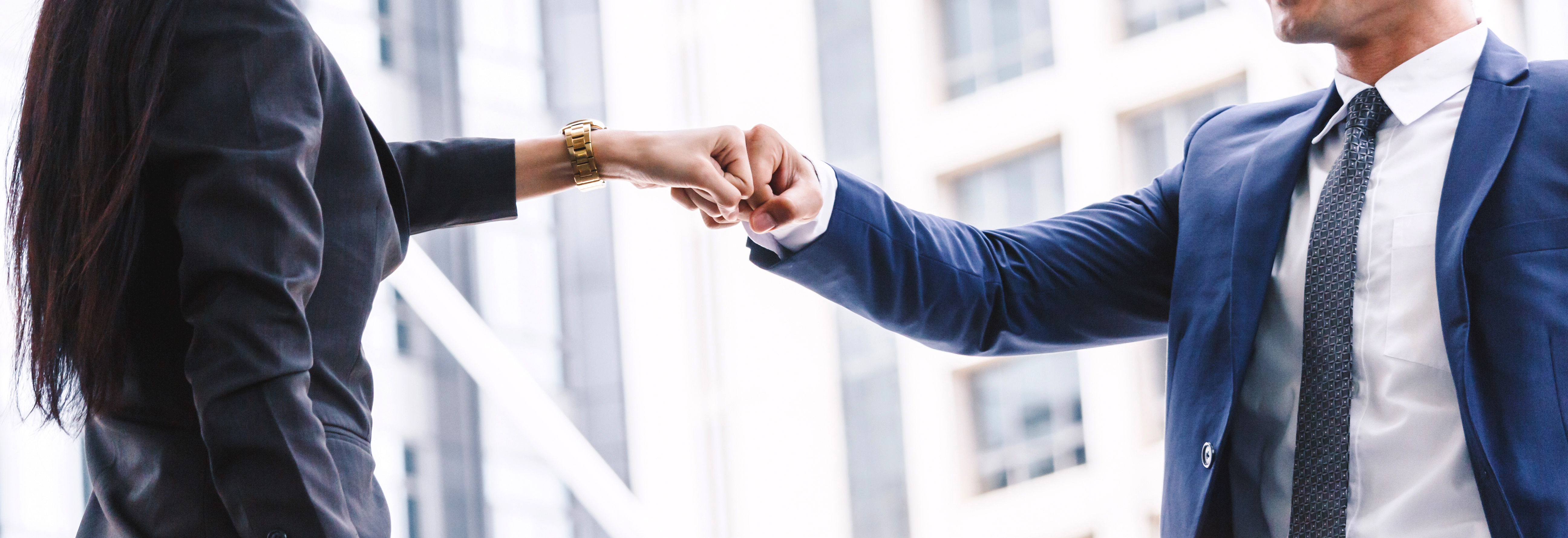 Business Zwei Geschäftspartner schließen einen Vertrag mit einem Handschlag vor einem Bürogebäude ab.