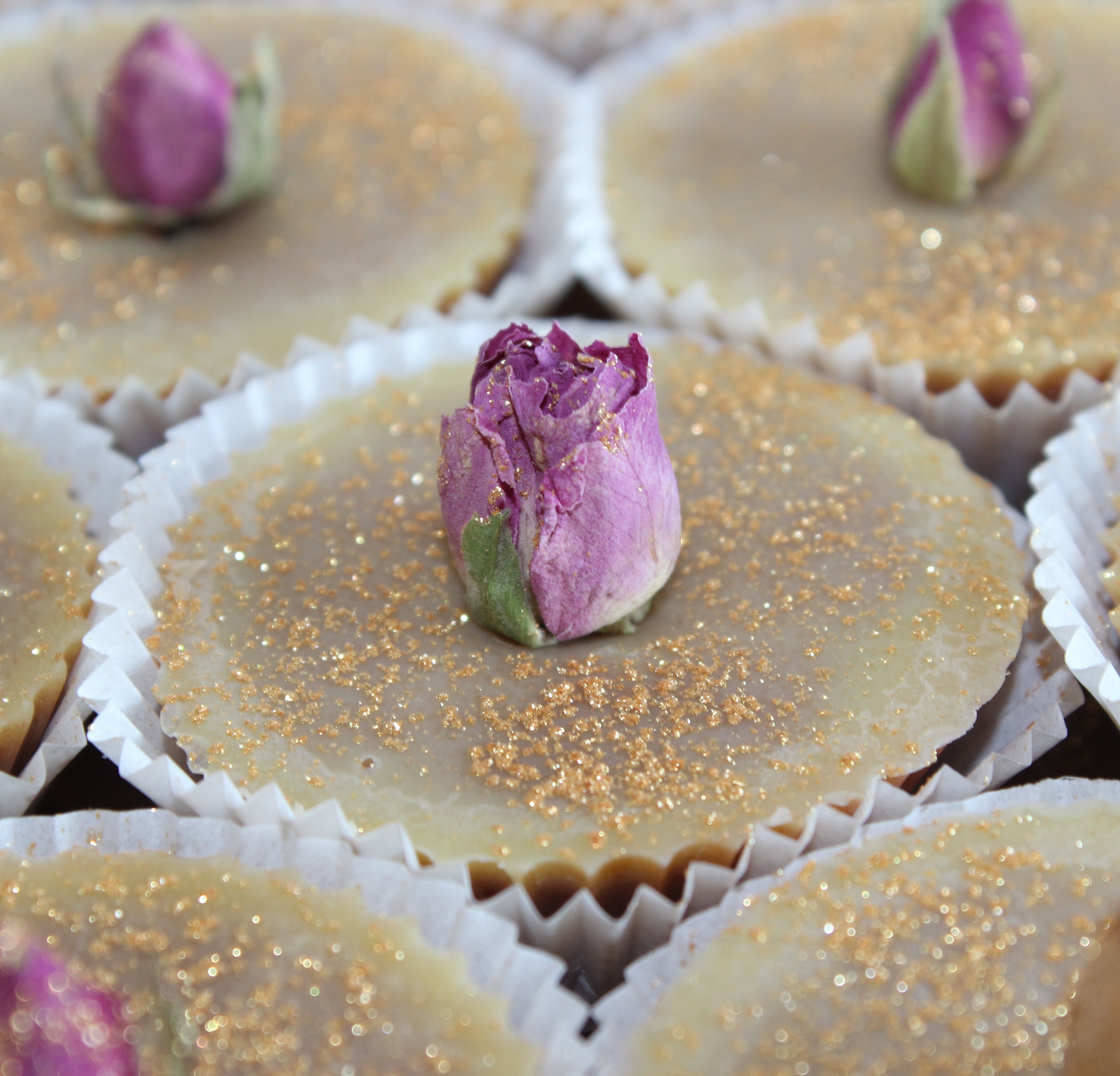 Badepralinen klein Rose Kleine Badepralinen mit Goldpuder in weißem Cupcake Papier mit eingesteckter Rose.