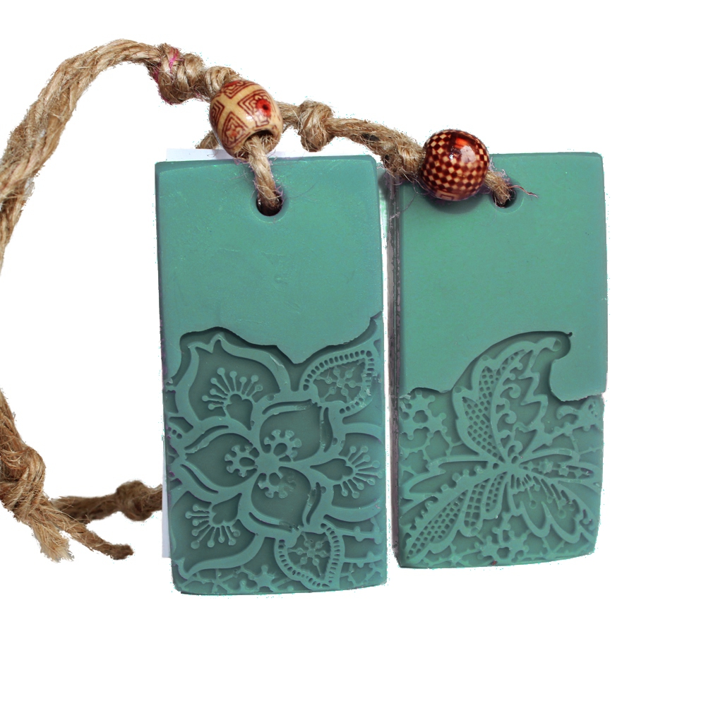 Grünes rechteckiges Seifenstück mit eingeprägter Blume an einer Kordel zum Aufhängen.